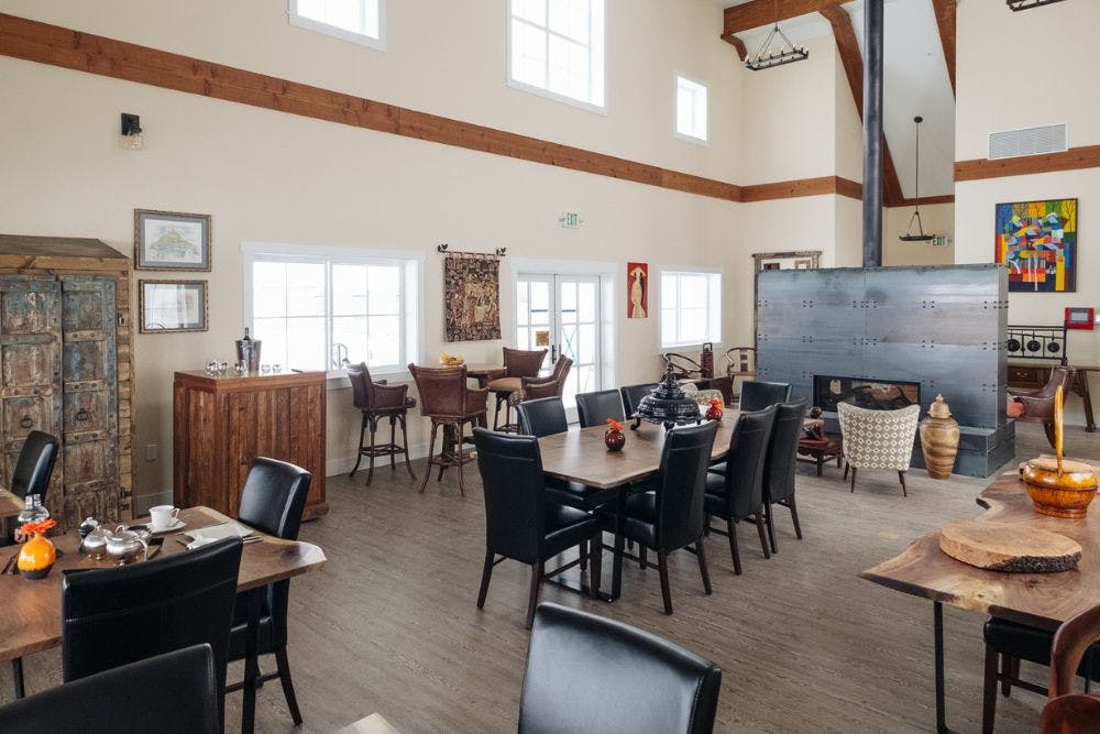 Spacious dining room with live edge walnut tables and black chairs and tall side wall with large windows