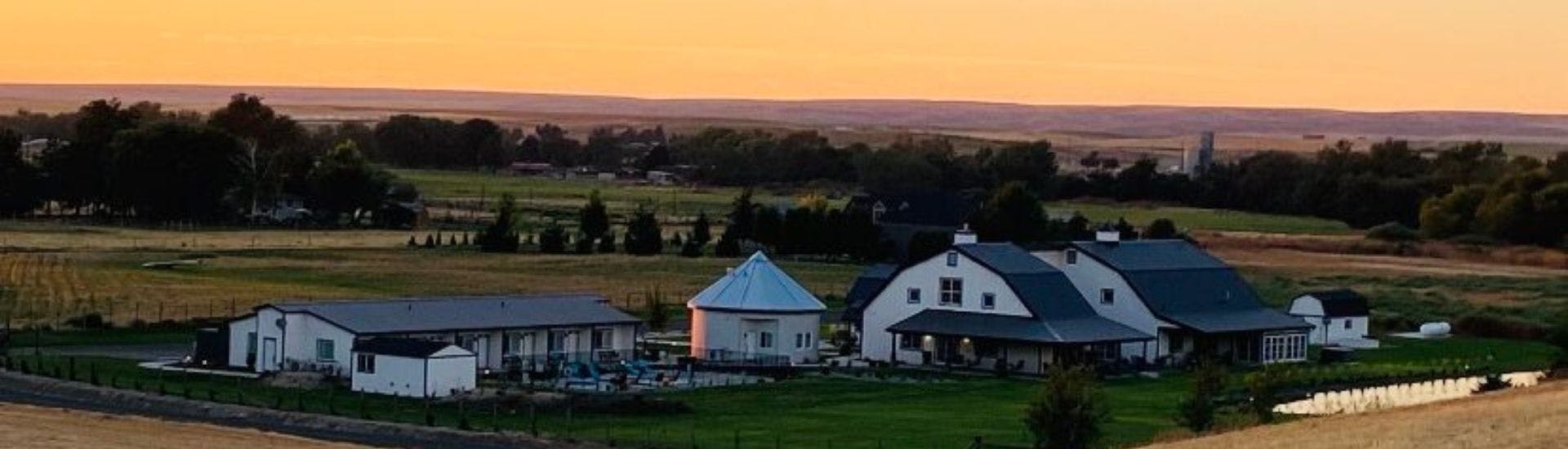 Panoramic view of an expansive bed and breakfast farm property with several buildings, pool, and silo