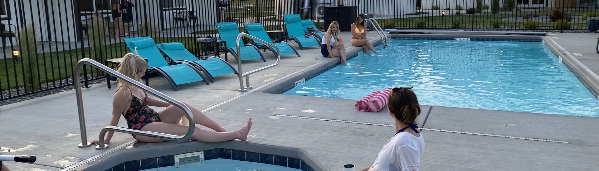 Men and woman sitting around and in a square pool and round hot tub