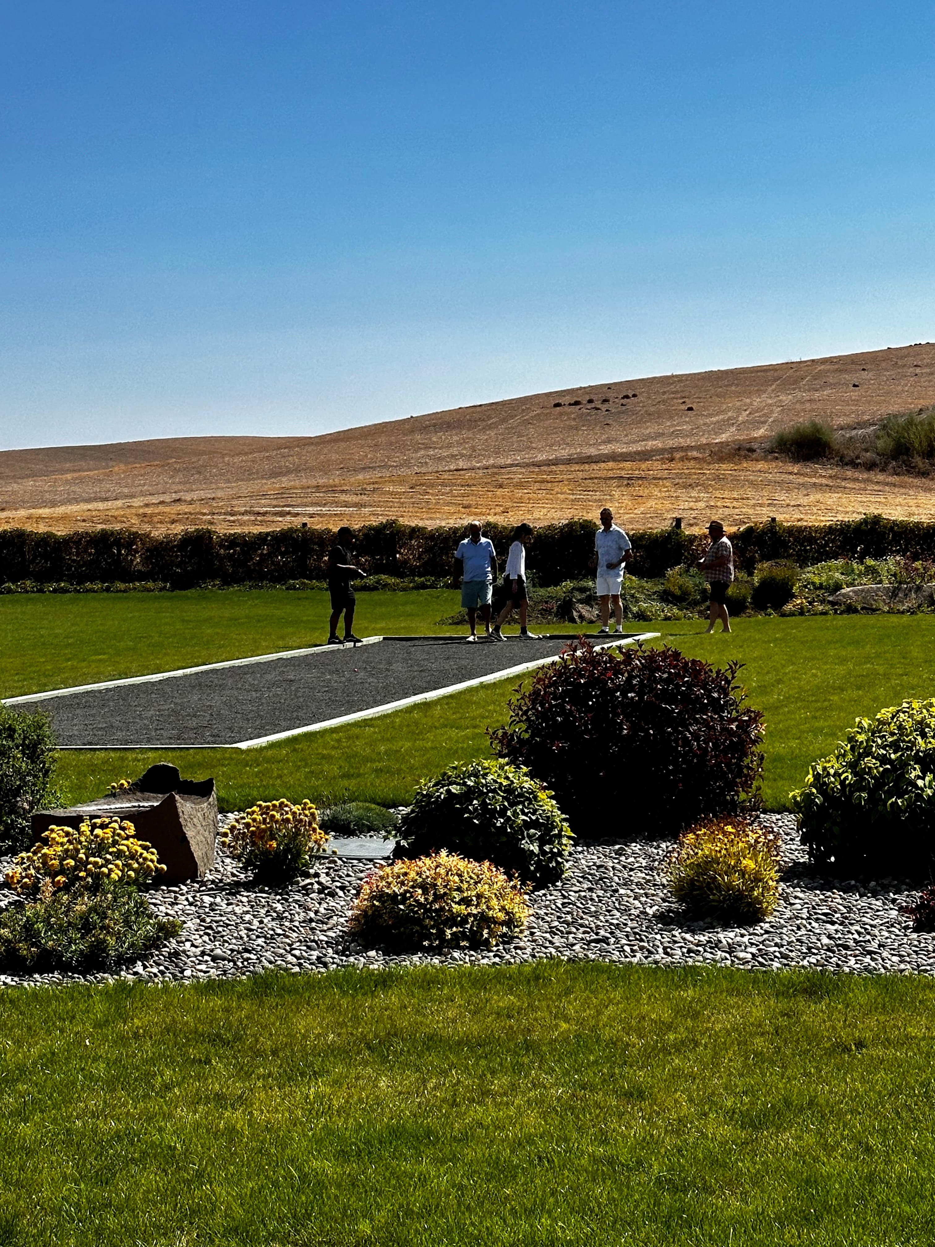 A group of people playing bocce ball outdoors under blue skies