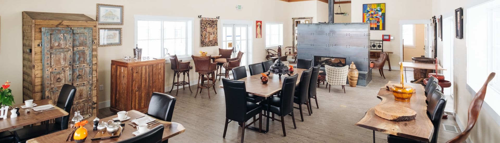 Large and spacious dining room with several tables with live edge walnut tops, black chairs and bright windows