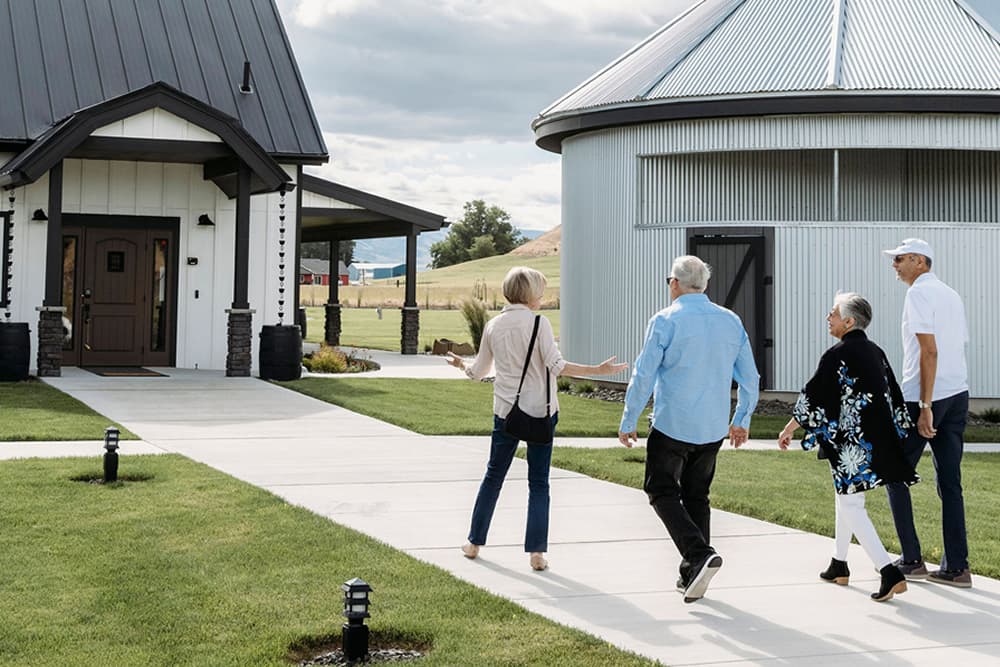 Men and woman walking and talking together moving toward a building with an overhang covering the door