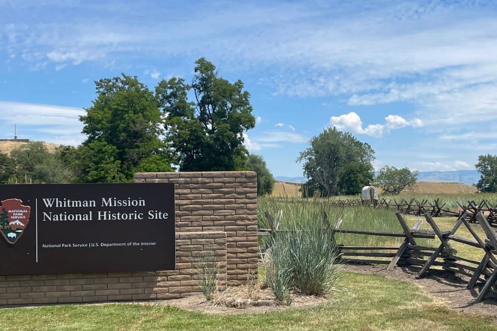 Historic site with large sign, wood fencing and a covered wagon