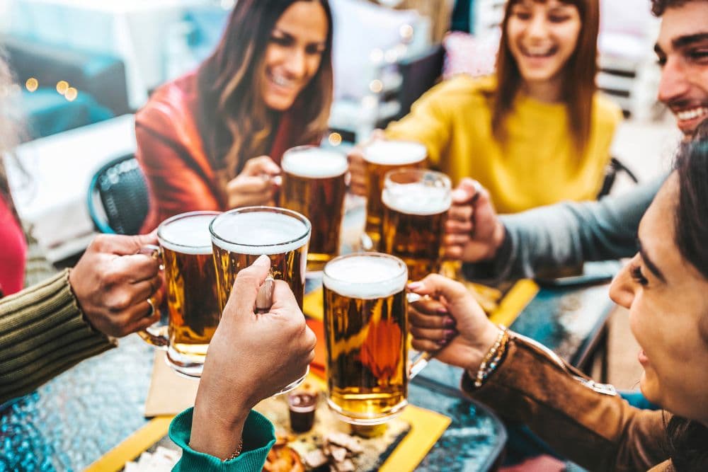 A group of people sitting at a table all drinking mugs of beer